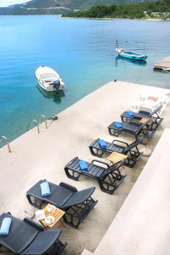 a group of lounge chairs and a boat in the water at Apartments Melany in Slano