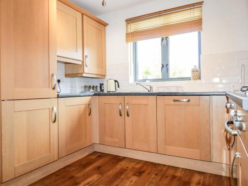 a kitchen with wooden cabinets and a window at Spinnaker in St Austell