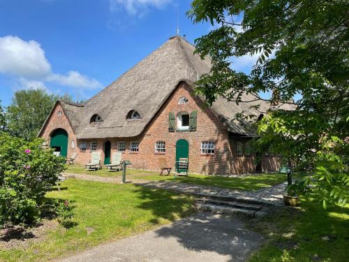 a large brick building with a thatched roof at Haubarg am Meer in Vollerwiek
