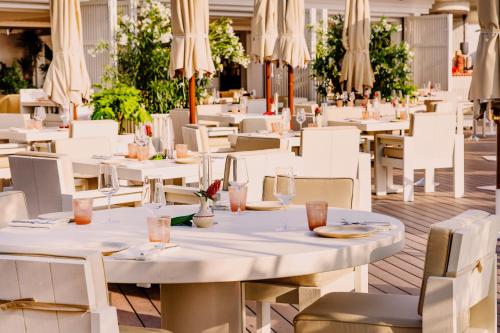 a restaurant with white tables and chairs and umbrellas at Cap d'Antibes Beach Hotel in Juan-les-Pins