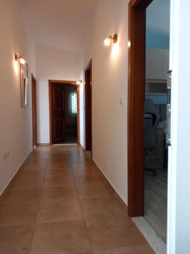 a hallway leading to a room with white walls and tile floors at Mitan apartman in Tučepi