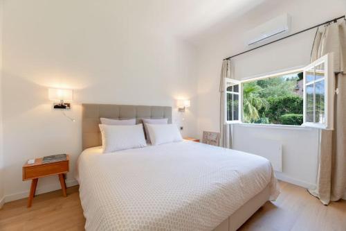 biała sypialnia z łóżkiem i oknem w obiekcie Maison Tropézienne en plein centre avec jardin et piscine w Saint-Tropez