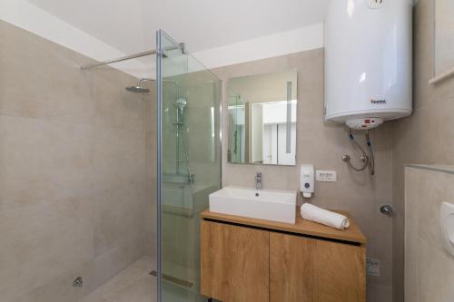 a bathroom with a sink and a glass shower at Apartment ACI Marina MILNA Brač in Milna