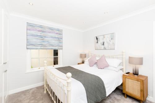 a white bedroom with a white bed and a window at Boutique Basement 1 Bed Flat, central location, free parking, Wi-Fi, Sky, Netflix in Leamington Spa