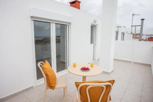 een tafel en stoelen in een kamer met een balkon bij One bedroom Apt in Almada with River view! in Almada