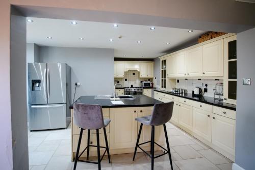 a kitchen with a refrigerator and two bar stools at Beldon House in Brigg