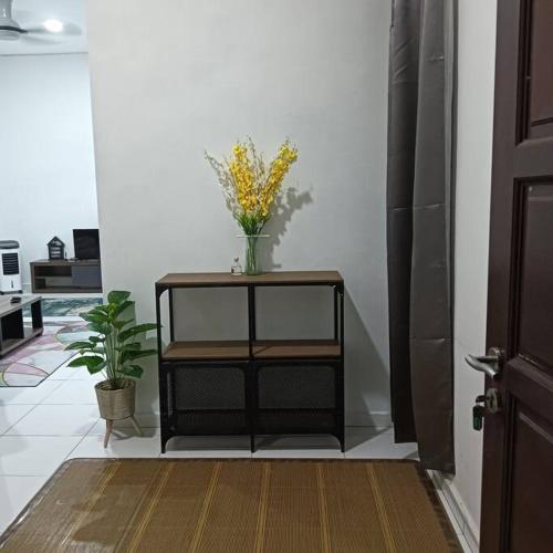 a black shelf with a vase of flowers on it at Damai Homestay in Kepala Batas