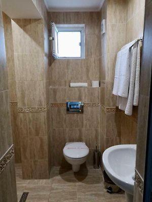 a bathroom with a toilet and a sink and a window at Къща за гости НЕЛ in Chernomorets