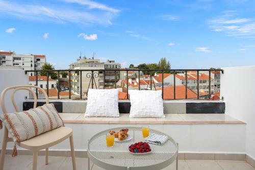 a balcony with a table and two glasses of orange juice at Almada Apt - Balcony with River View by Lisbeyond in Almada