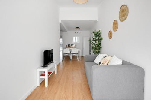 a living room with a gray couch and a television at Almada Apt - Balcony with River View by Lisbeyond in Almada