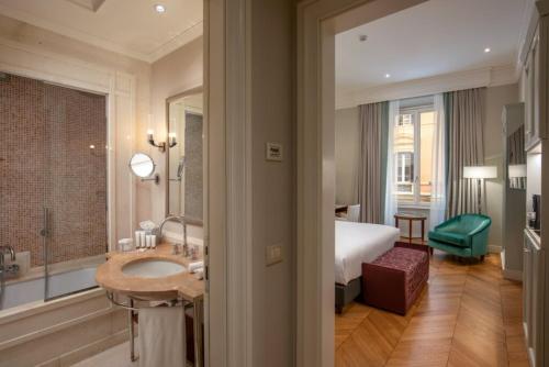 Habitación de hotel con baño con cama y lavamanos en Rose Garden Palace Roma by OMNIA hotels, en Roma