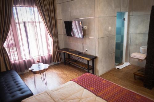 a room with a bed and a television and a couch at Pariban Hotel in Berastagi