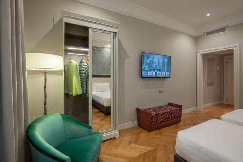 a room with a green chair and a mirror at Rose Garden Palace Roma by OMNIA hotels in Rome