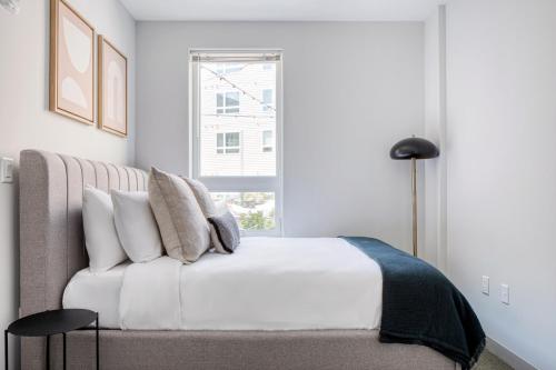 a white bedroom with a bed and a window at Brighton 1BR w WD Gym nr T Shops Dining BOS-435 in Boston