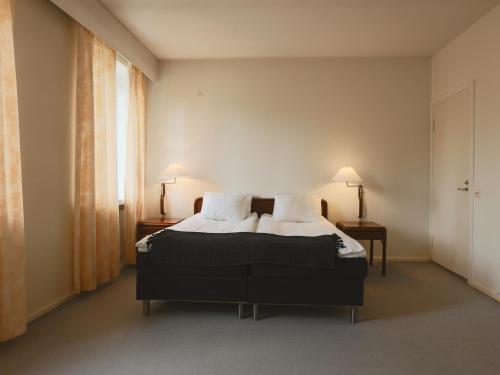 een slaapkamer met een bed met 2 lampen en een raam bij Myllykosken Kerho Oy in Kouvola
