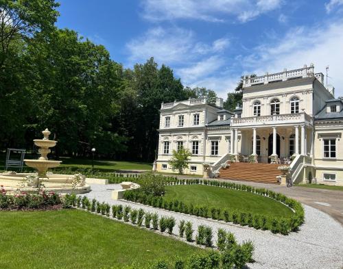 una gran mansión blanca con una fuente en el patio en Pałac Chojnata, en Wola Chojnata