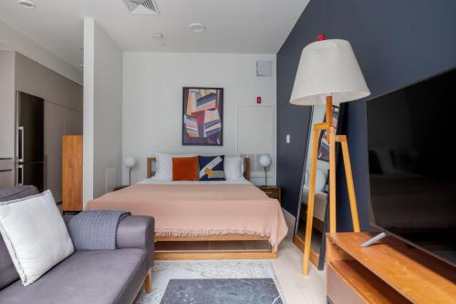 a bedroom with a bed and a couch and a tv at South Boston studio w wd nr red line BOS-886 in Boston