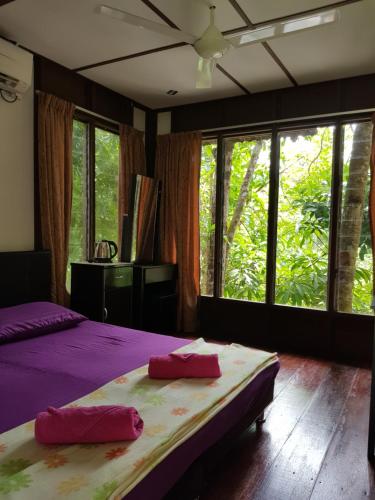 a bedroom with two beds with purple sheets and windows at D'Impiana Riverview Chalet # Lenggong in Kampong Ulu Jepai