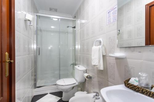 y baño con ducha, aseo y lavamanos. en Hotel Oasis en Conil de la Frontera