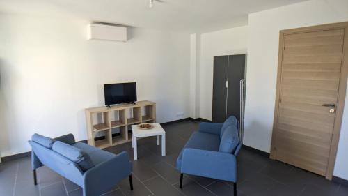 un salon avec deux chaises bleues et une télévision dans l'établissement Chambre urbaine dans Maison Moderne, à Dammarie-les-Lys