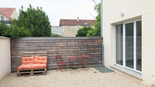 deux chaises rouges et une table devant une clôture dans l'établissement Chambre urbaine dans Maison Moderne, à Dammarie-les-Lys