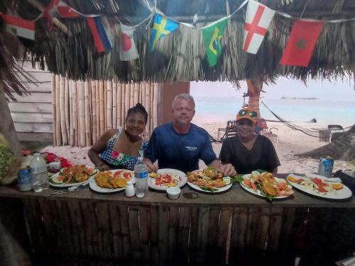 a group of people sitting at a table with plates of food at Isla diablo cabañas en la orilla del mar baño compartido in Cagantupo