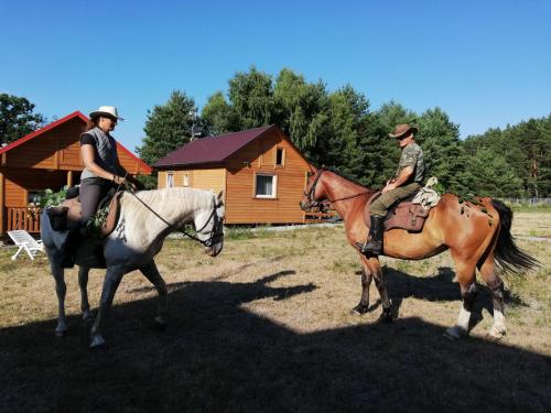 twee mensen op paarden voor een hut bij AgroDana Malinka in Wisełka