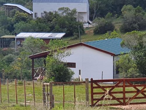 een witte schuur met een hek in een veld bij Serena in Villa Serrana