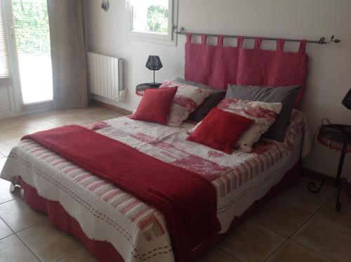 une chambre avec un grand lit avec une tête de lit rouge dans l'établissement GITE MAS URANIE, à Le Soler