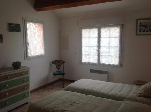 - une chambre avec 2 lits, une commode et 2 fenêtres dans l'établissement GITE MAS URANIE, à Le Soler