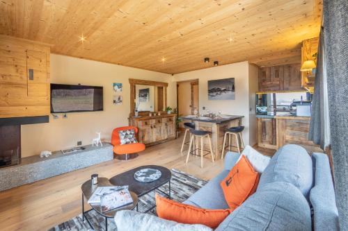 un salon avec un canapé bleu et une cuisine dans l'établissement Les Corneilles - Appartement, à Megève