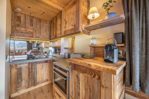 une cuisine avec des armoires en bois et un comptoir dans l'établissement Les Corneilles - Appartement, à Megève