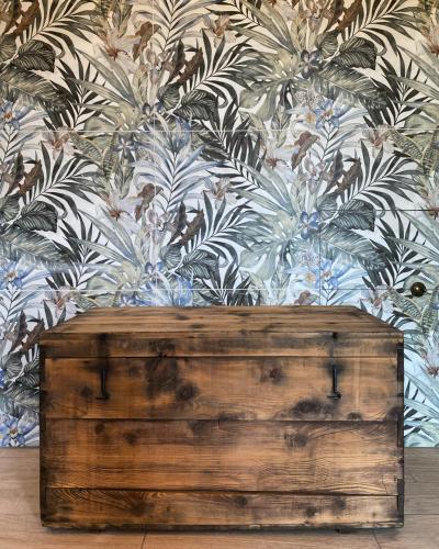 a wooden chest in front of a floral wall at Agriturismo Casa del Principe in Torre Bormida