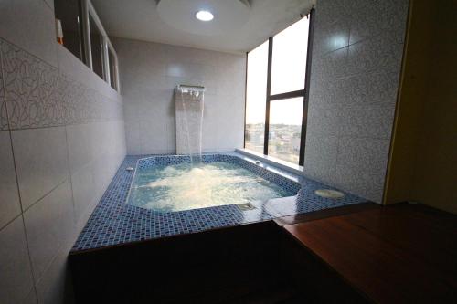 a bathroom with a large tub with a window at Hotel Golden Vista in Santo Domingo de los Colorados