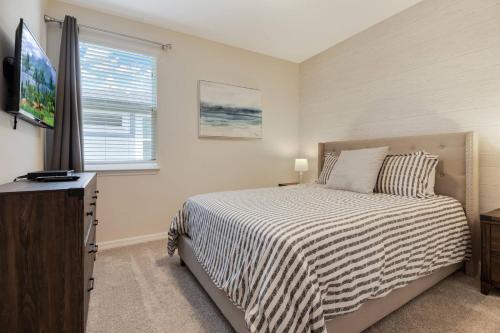 1 dormitorio con 1 cama, TV y ventana en Large Home Up to 20 Guests BBQ Heated Pool SPA, en Kissimmee
