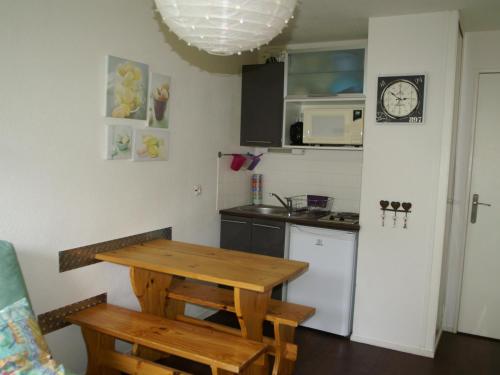 une cuisine avec une table en bois et un réfrigérateur dans l'établissement Studio central avec balcon et vues sur pistes - 3 couchages - FR-1-557-44, à Les Adrets