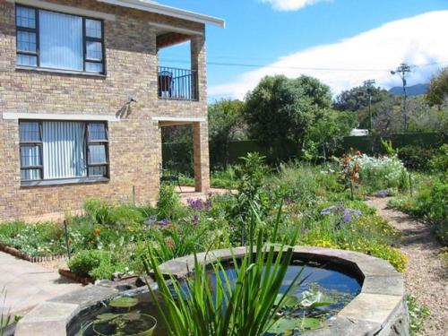 a garden with a pond in front of a house at Ascot Gardens Self Catering in Cape Town