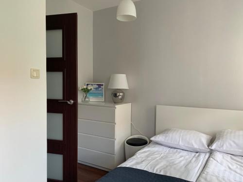 ソポトにあるMEwa Apartment Polnaのベッドルーム1室(ベッド1台、ドレッサー、ランプ付)