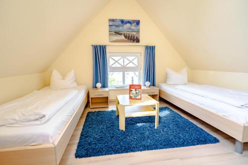 2 Betten in einem Zimmer mit blauem Teppich in der Unterkunft Die Kornblume in Zingst