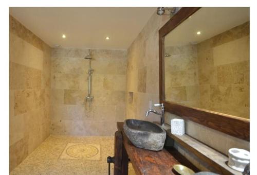 une salle de bain avec un lavabo et un grand miroir dans l'établissement Gite La Grange du Pech, à Lacour