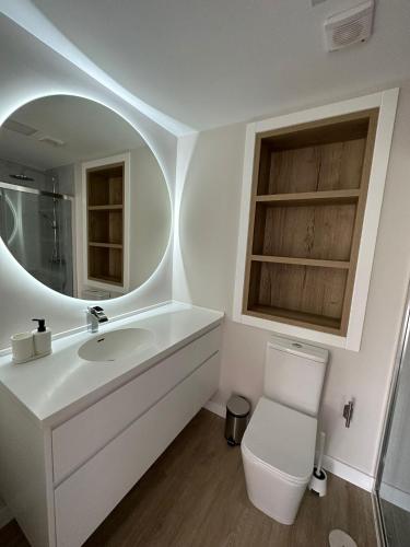 a bathroom with a sink and a toilet and a mirror at Lagarteira in Sanxenxo