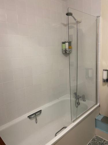 a bathroom with a bath tub with a glass shower door at Lovely room in Chelsea in London