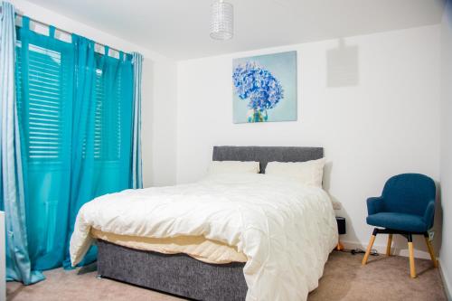 een slaapkamer met een bed en een blauwe stoel bij Beautiful 5 Bedroom House in Glasgow in Cambuslang