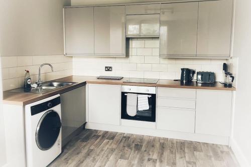 a white kitchen with a sink and a dishwasher at Views over the Peak District Apartment with WIFI in Sheffield
