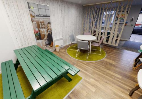 a room with a green bench and tables and chairs at iQ Ty Willis House in Bangor in Bangor