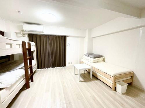 大阪市にあるSUNRISE APT 新大阪駅から徒歩5分観光都市へのアクセス抜群Simply Guest Room Shin-Osakaの二段ベッド2台とテーブルが備わる客室です。