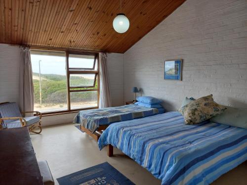 um quarto com 2 camas e uma grande janela em Our holiday home at the beach em Port Alfred