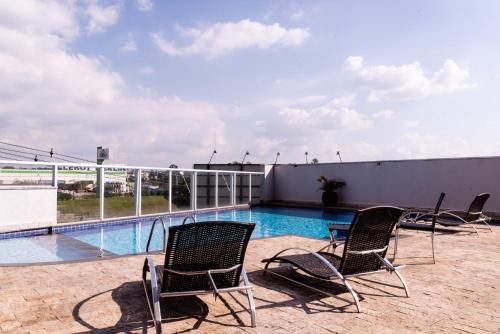 a patio with chairs and a swimming pool on a building at Loft Campolim in Sorocaba