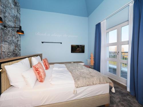 una camera da letto con un letto con pareti blu e una finestra di Seebrücke Heringsdorf - Appartement mit 2 Schlafzimmern und Terrasse S21 a Heringsdorf