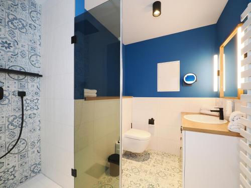 La salle de bains est pourvue de murs bleus, de toilettes et d'un lavabo. dans l'établissement Seebrücke Heringsdorf - Appartement mit 2 Schlafzimmern und Terrasse S21, à Heringsdorf